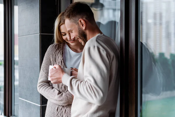 Alegre pareja sosteniendo tazas de café fuera - foto de stock