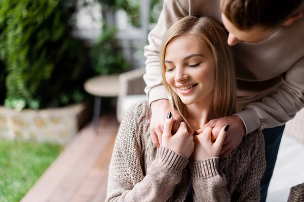 Enfoque selectivo del hombre cogido de la mano con chica alegre fuera - foto de stock