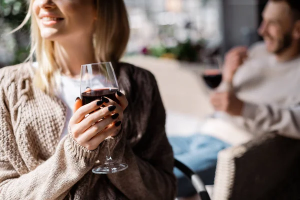 Vista recortada de niña feliz sosteniendo vaso con vino tinto cerca de hombre - foto de stock