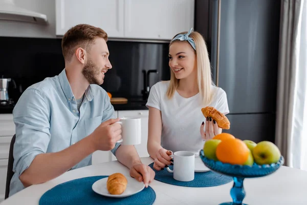 Feliz mujer y hombre mirándose el uno al otro cerca de sabroso desayuno - foto de stock