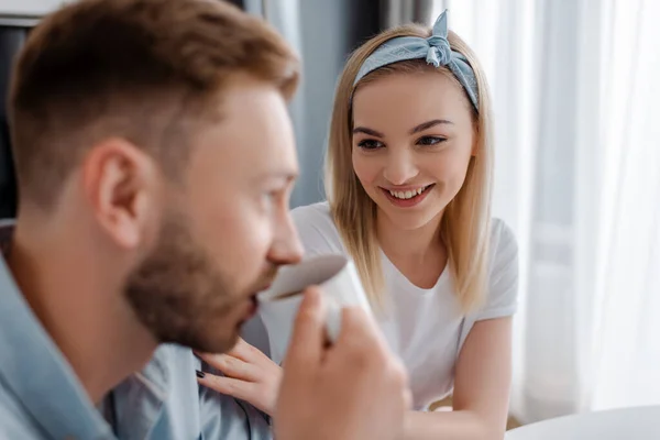 Selective focus of happy woman looking at man drinking coffee — Stock Photo