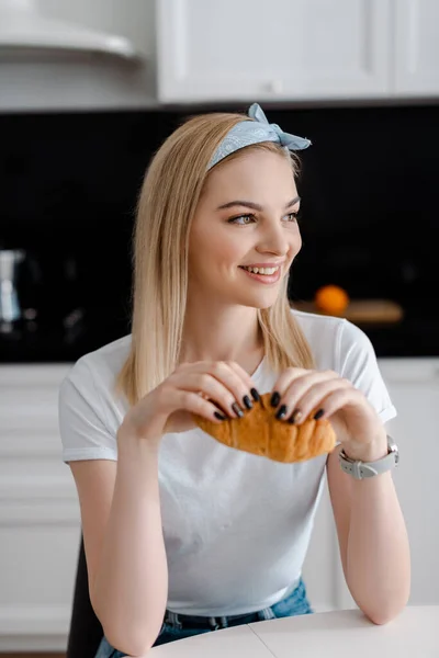 Glückliche Frau hält leckeres Croissant in der Hand und schaut weg — Stockfoto