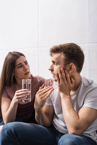 Triste pareja con vaso de agua en casa durante el calor del verano - foto de stock