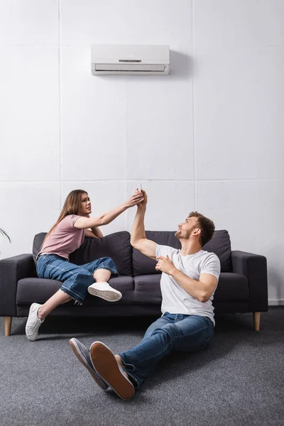 Couple en colère avec télécommande à la maison avec climatiseur cassé — Photo de stock