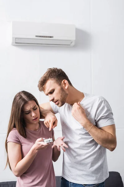 Jeune couple souffrant de chaleur à la maison avec climatiseur cassé — Photo de stock