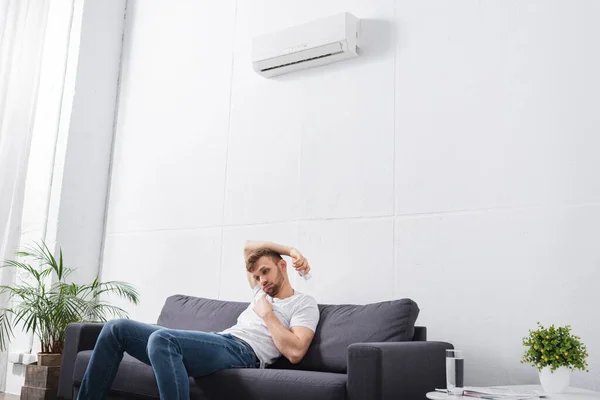 Sad man feeling uncomfortable with broken air conditioner at home during summer heat — Stock Photo