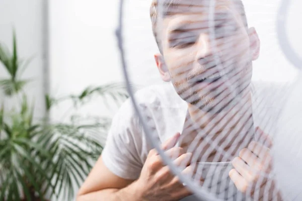 Glücklicher Mann, der sich bei Sommerhitze mit elektrischem Ventilator zu Hause wohl fühlt, selektiver Fokus — Stockfoto