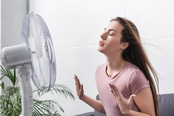 Schönes Mädchen fühlt sich bei Sommerhitze mit elektrischem Ventilator wohl — Stockfoto