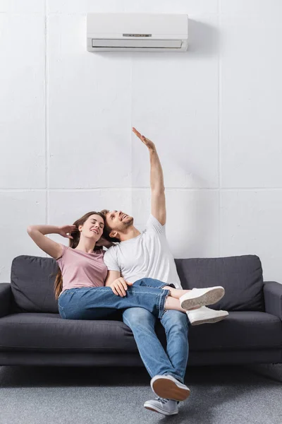 Jovem casal feliz em casa com ar condicionado — Fotografia de Stock