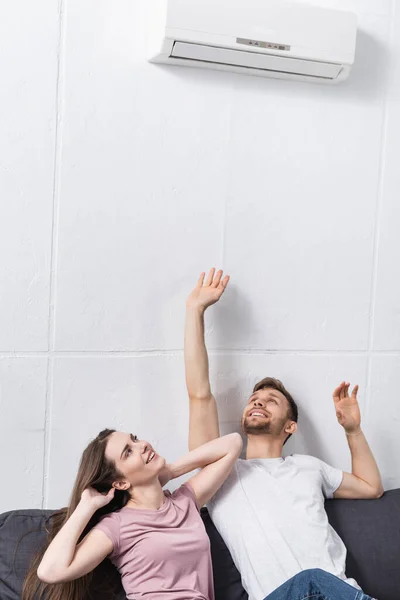 Feliz pareja en casa con aire acondicionado - foto de stock