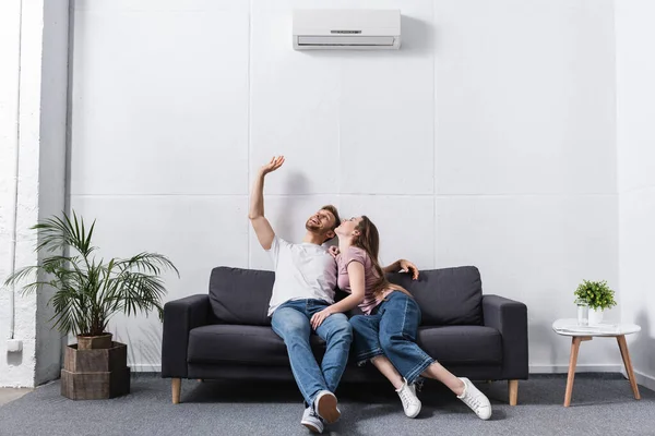 Smiling girlfriend and boyfriend hugging at home with air conditioner — Stock Photo