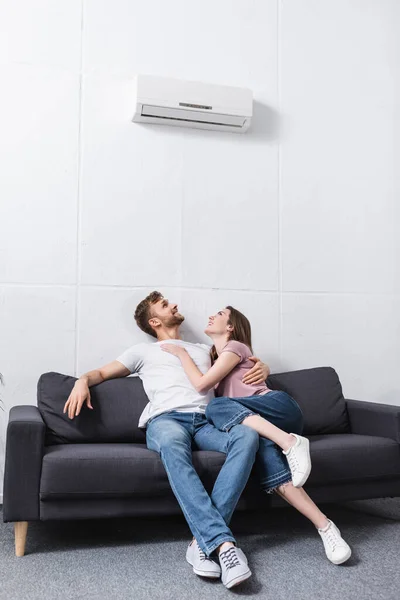 Happy girlfriend and boyfriend hugging at home with air conditioner — Stock Photo