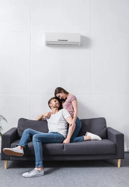 Happy girlfriend and boyfriend hugging at home with air conditioner — Stock Photo