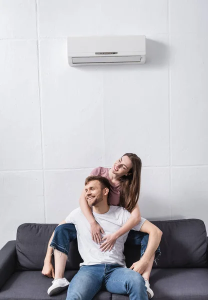 Улыбающаяся пара обнимается дома с кондиционером — стоковое фото