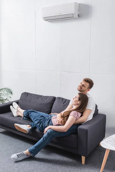 Jeune couple heureux étreignant à la maison avec climatiseur — Photo de stock