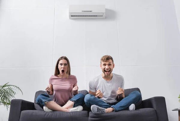 Excitada pareja gritando en casa con aire acondicionado - foto de stock