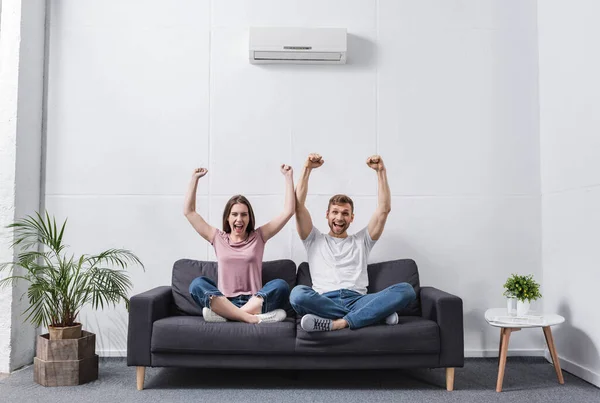 Excited shouting couple at home with air conditioner — Stock Photo