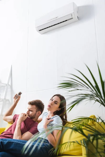 Upset couple sitting home with broken air conditioner — Stock Photo