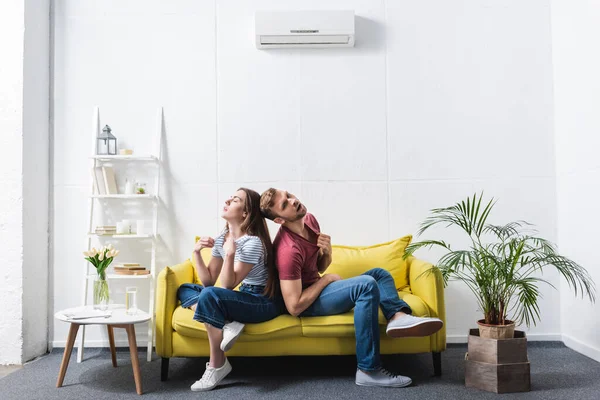 Casal exausto sofrendo de calor enquanto sentado em casa com ar condicionado quebrado — Fotografia de Stock