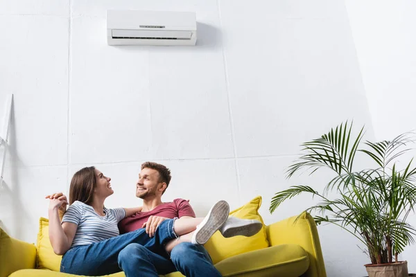 Heureux jeune couple câlin à la maison avec climatiseur — Photo de stock