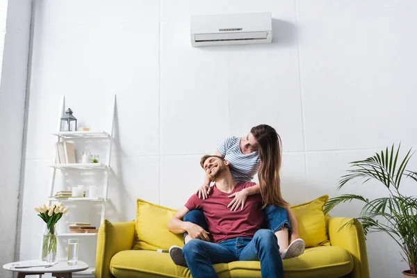 Coppia sorridente che si abbraccia a casa con climatizzatore — Foto stock