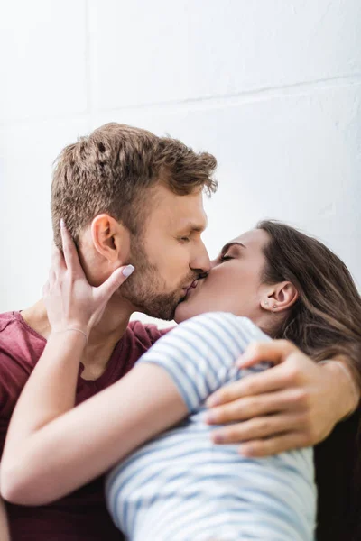 Feliz joven pareja abrazándose y besándose en casa - foto de stock