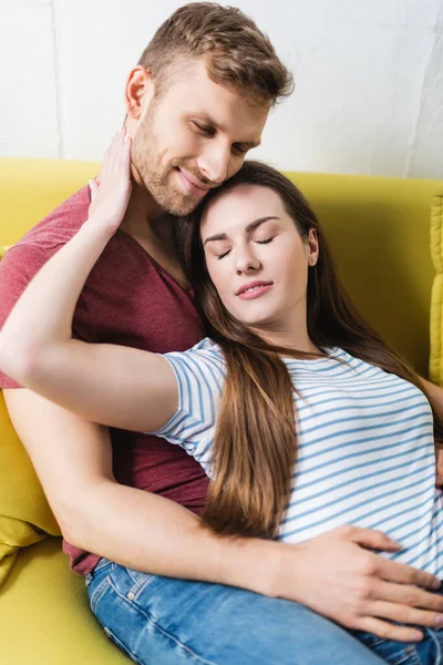 Sonriente hermosa joven pareja abrazando en casa - foto de stock