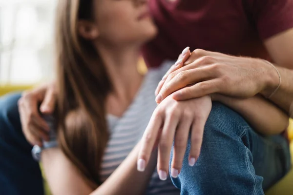 Abgeschnittene Ansicht von Paar, das sich zu Hause umarmt und Händchen hält, selektiver Fokus — Stockfoto