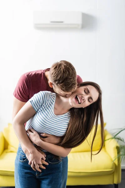 Riendo hermosa joven pareja abrazándose en casa - foto de stock