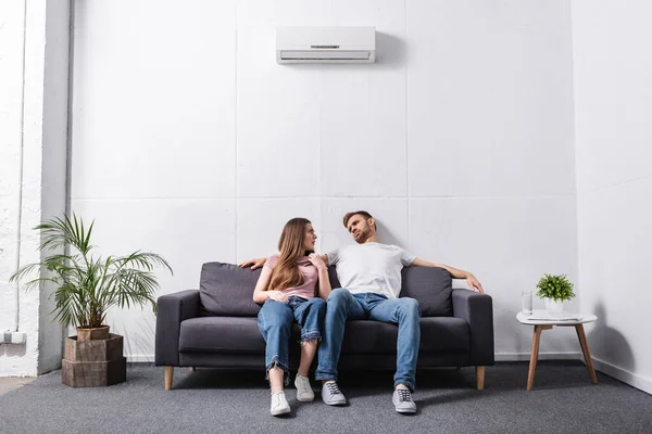 Pareja joven que sufre de calor mientras está sentada en casa con el aire acondicionado roto - foto de stock