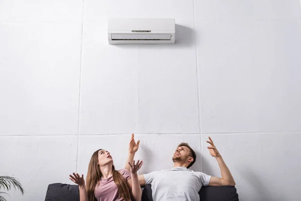 Irritated couple suffering from heat at home with broken air conditioner — Stock Photo