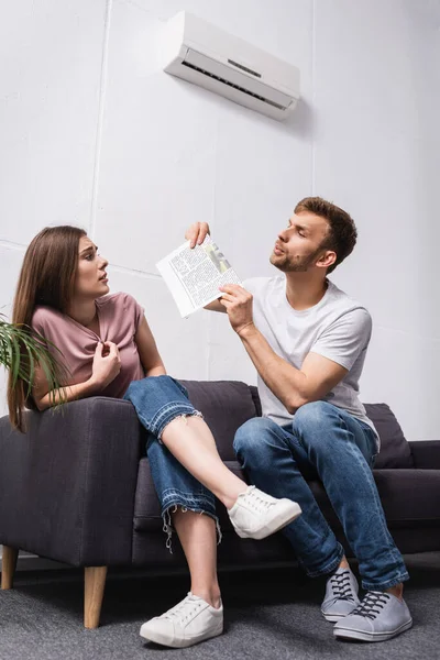 Sad young couple suffering from heat at home with broken air conditioner — Stock Photo