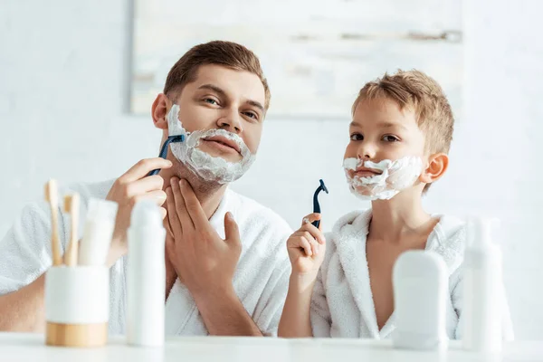 Enfoque selectivo de padre e hijo afeitándose en el baño juntos - foto de stock