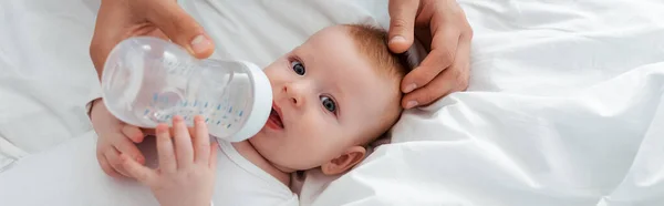 Abgeschnittene Ansicht des Vaters, der entzückende kleine Jungen aus der Babyflasche füttert, horizontales Bild — Stockfoto