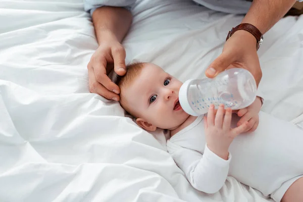 Corte vista de homem alimentando bonito pequeno filho de bebê garrafa com leite — Fotografia de Stock