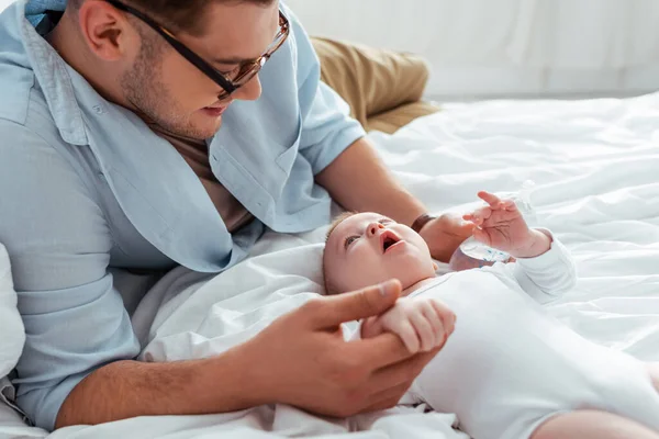 Young father touching cute baby boy while holding baby bottle with milk — Stock Photo