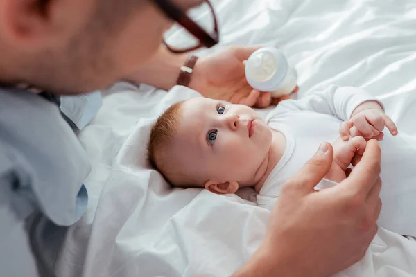 Vista aerea del padre che tiene in mano il biberon con latte vicino all'adorabile piccolo figlio — Foto stock