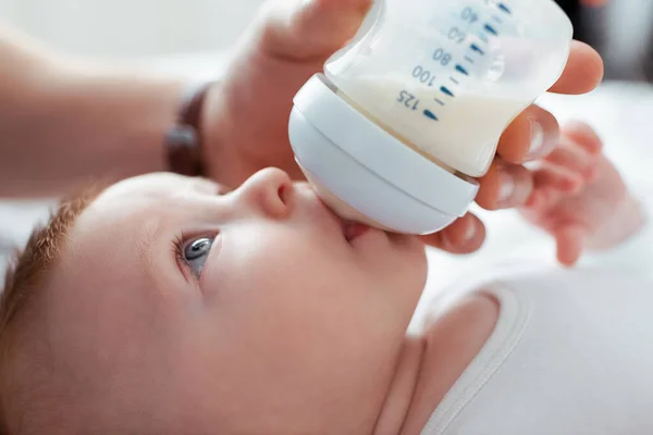 Cropped view of man feeding adorable infant from baby bottle with milk — Stock Photo