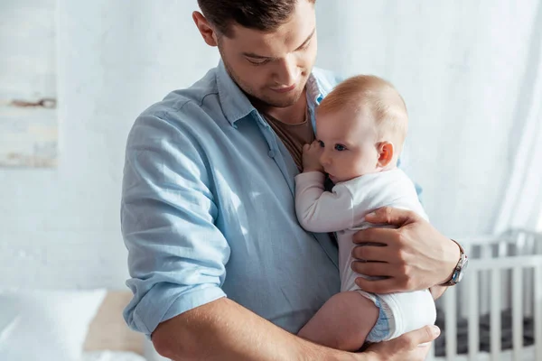 Young man holding on hands and embracing adorable little son — Stock Photo