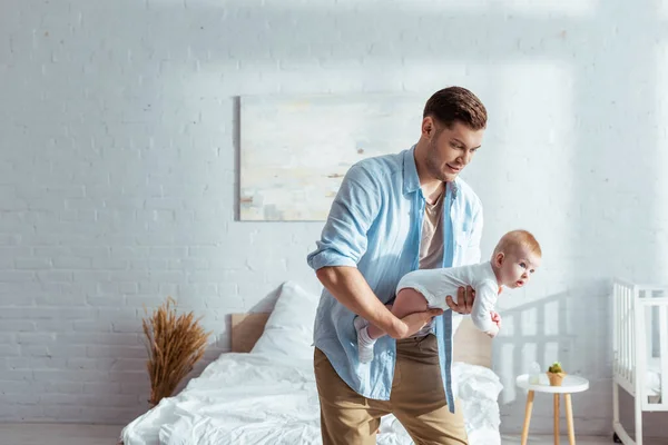 Young father holding adorable little son in bedroom — Stock Photo