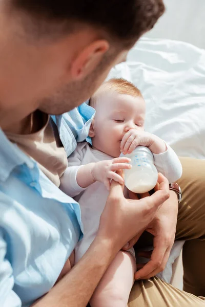 High angle view of father feeding cute little son with milk from baby bottle — Stock Photo