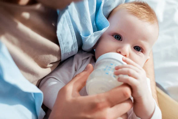 Cropped view of father feeding son with milk from baby bottle — Stock Photo
