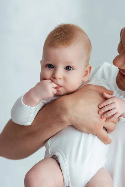 Vue recadrée du père tenant mignon petit garçon avec les doigts dans la bouche — Photo de stock