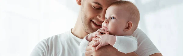 Horizontal image of happy father with closed eyes holding little baby boy on hands — Stock Photo