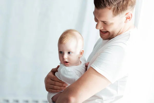 Lächelnder junger Vater mit süßem Baby im Schlafzimmer — Stockfoto