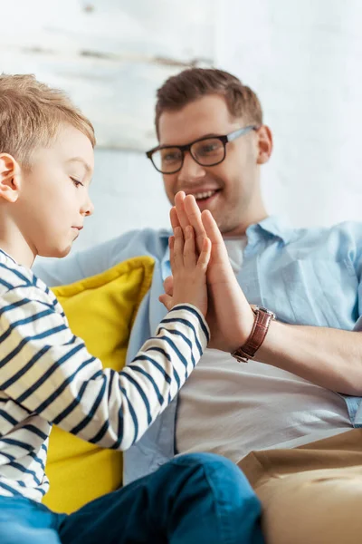 Selective focus of smiling man giving high five to adorable son — Stock Photo