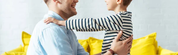 Recortado vista de niño cogido de la mano en hombros de padre sonriente, imagen horizontal - foto de stock