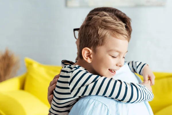 Happy boy embracing father with closed eyes — Stock Photo