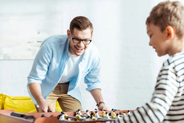 Selective focus of happy man playing table football with son — Stock Photo