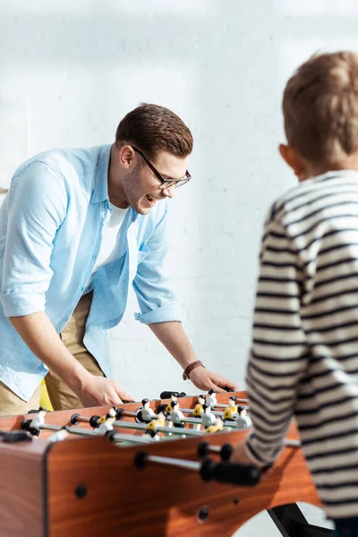 Selective focus of cheerful man playing table football with son — Stock Photo